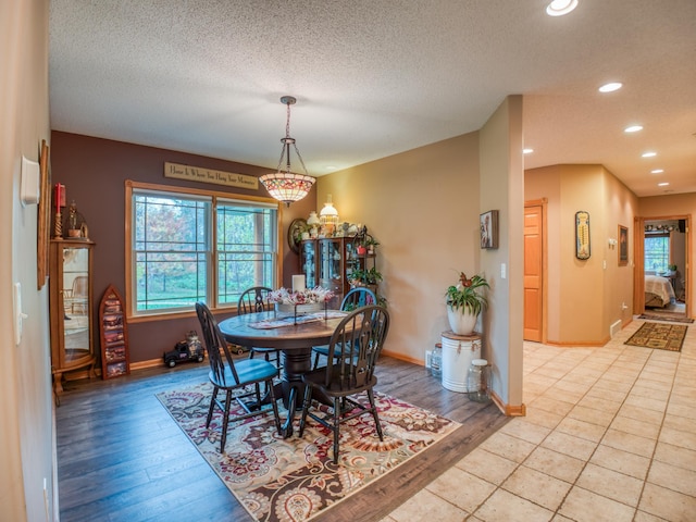 dining room with baseboards, recessed lighting, a textured ceiling, and light wood-style floors