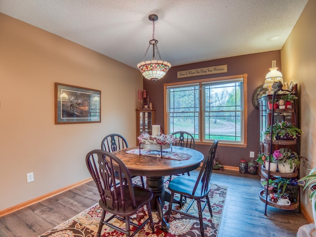 dining area with a textured ceiling, baseboards, and wood finished floors