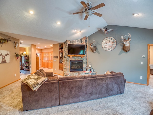 carpeted living area featuring ceiling fan, baseboards, lofted ceiling, a fireplace, and a textured ceiling