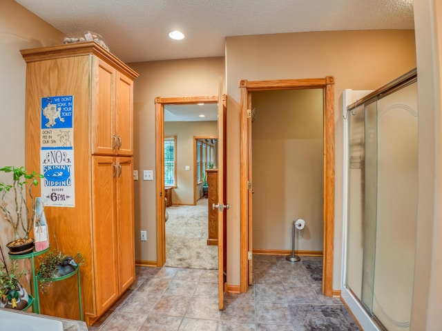 full bath with tile patterned flooring, baseboards, a stall shower, and a textured ceiling