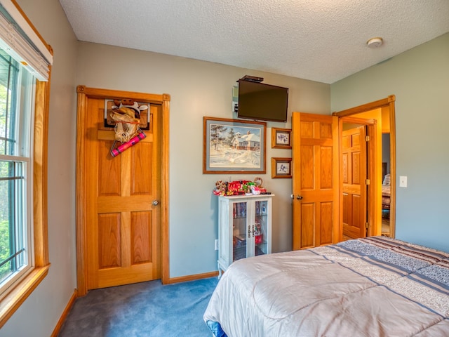 carpeted bedroom with a textured ceiling and baseboards