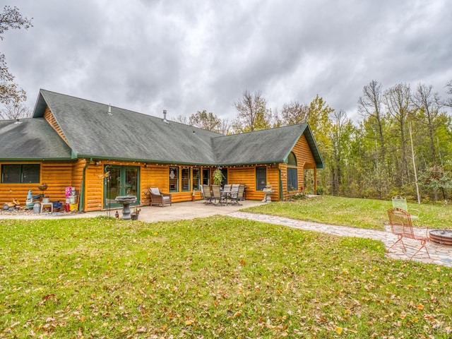 rear view of property with a fire pit, a patio area, a lawn, and a shingled roof