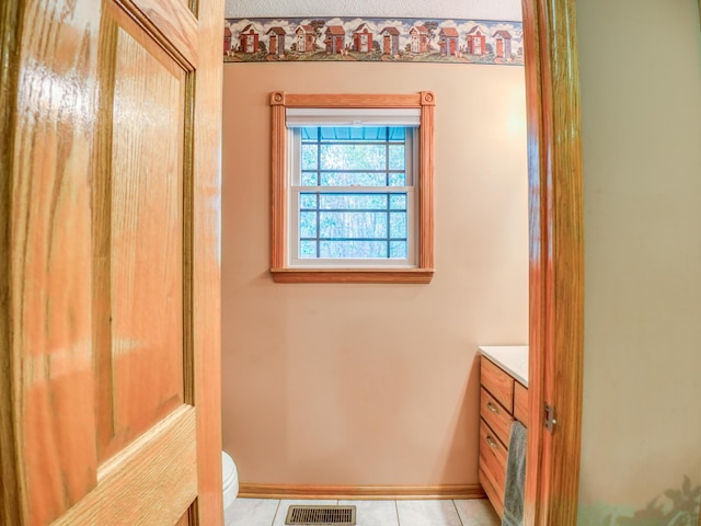 bathroom with tile patterned flooring, visible vents, baseboards, toilet, and vanity