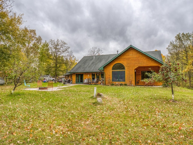 rear view of house with log veneer siding, a yard, and a patio area