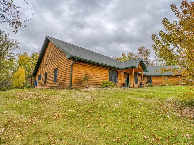 back of property featuring a lawn and a shingled roof