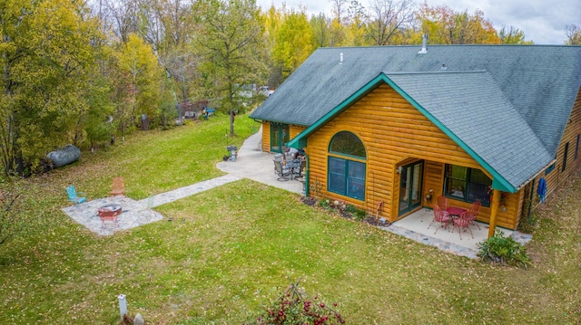 view of front of property with a patio, a front yard, and a shingled roof