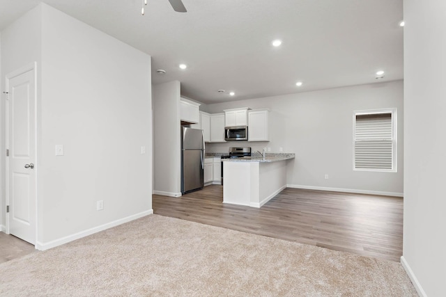 kitchen with white cabinets, open floor plan, appliances with stainless steel finishes, and light carpet