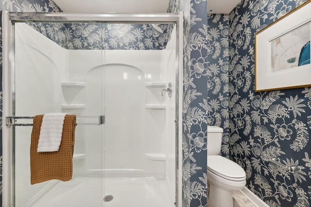 full bath with wallpapered walls, toilet, and a stall shower