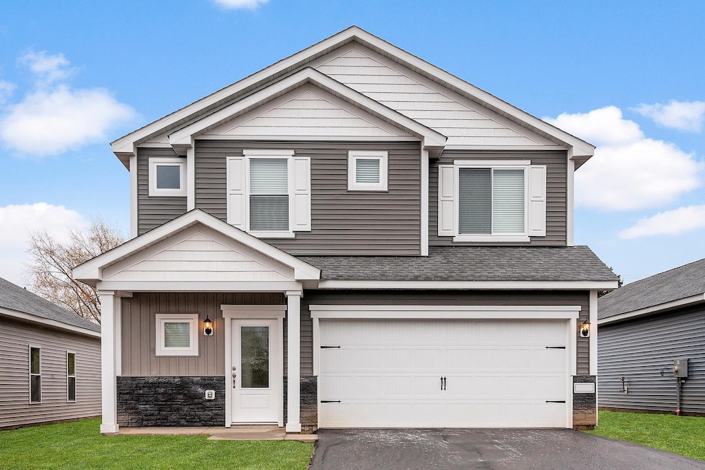 view of front facade featuring driveway, a shingled roof, a garage, stone siding, and board and batten siding