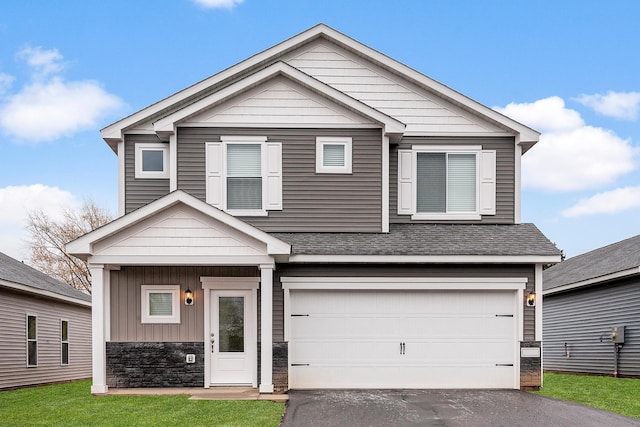 view of front facade featuring driveway, a shingled roof, a garage, stone siding, and board and batten siding