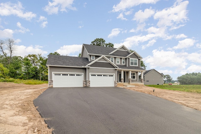 craftsman house with a porch, an attached garage, stone siding, aphalt driveway, and board and batten siding