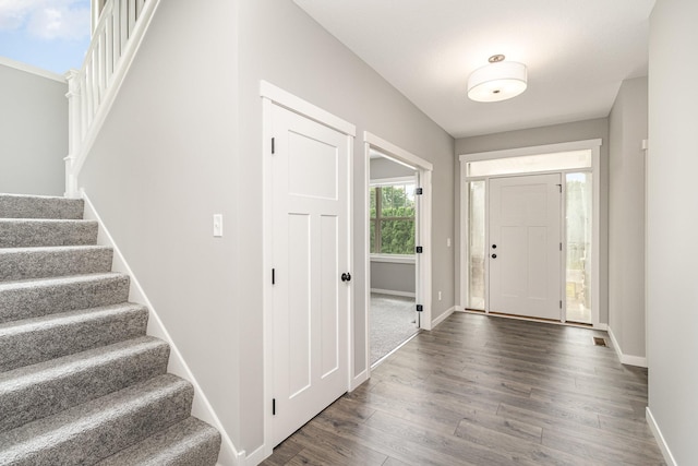 foyer entrance with visible vents, stairs, dark wood-type flooring, and baseboards