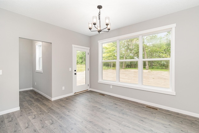 interior space with light wood-style flooring, a notable chandelier, visible vents, and baseboards