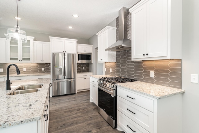 kitchen featuring a sink, dark wood-style floors, stainless steel appliances, wall chimney exhaust hood, and white cabinets