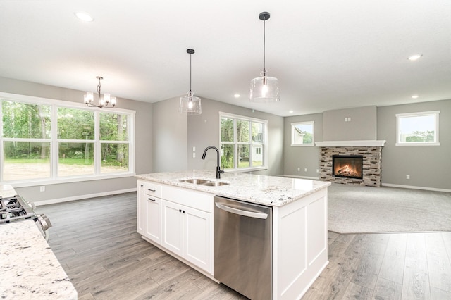 kitchen featuring light wood-style flooring, a sink, a stone fireplace, white cabinets, and appliances with stainless steel finishes