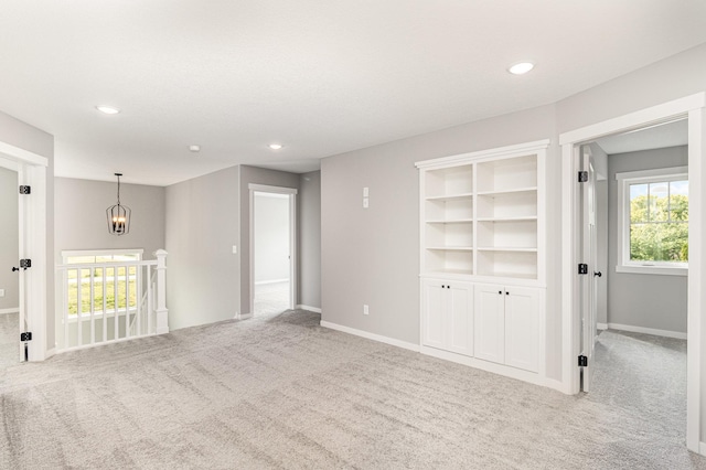 spare room with a notable chandelier, carpet flooring, recessed lighting, and baseboards