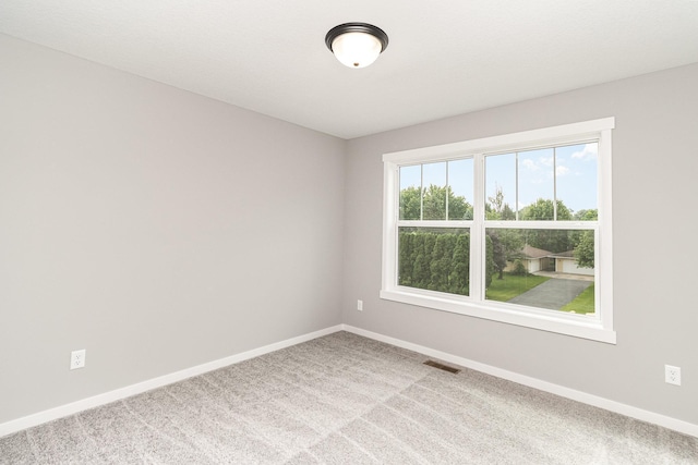 carpeted spare room with visible vents and baseboards