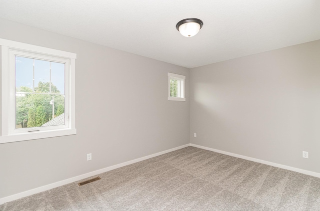 carpeted spare room with visible vents and baseboards