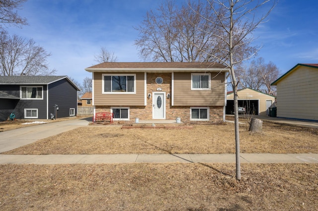 bi-level home featuring concrete driveway, an outbuilding, and a garage