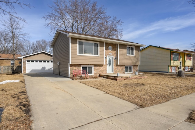 bi-level home featuring a garage, stone siding, an outbuilding, and fence