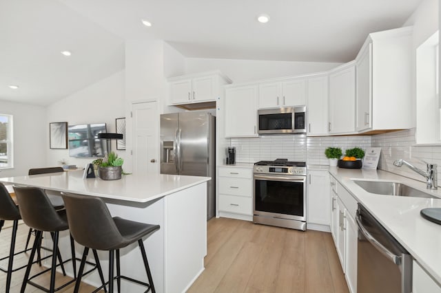 kitchen featuring a sink, appliances with stainless steel finishes, white cabinets, and vaulted ceiling