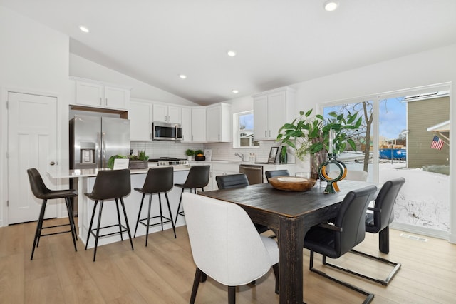 dining room with visible vents, recessed lighting, light wood-type flooring, and vaulted ceiling