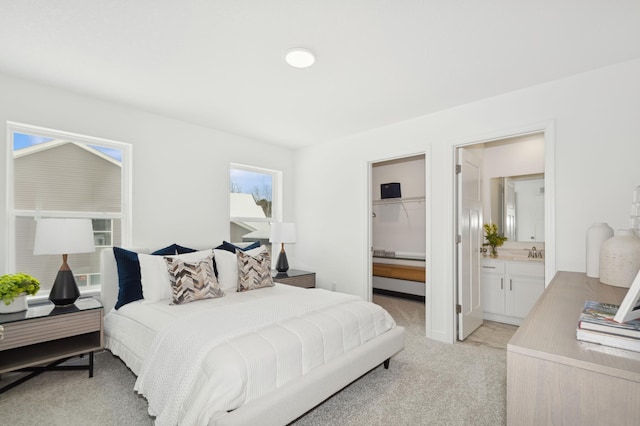 bedroom featuring a sink, a spacious closet, a closet, light colored carpet, and connected bathroom