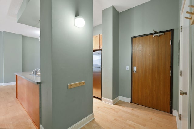 hall with light wood-type flooring and baseboards