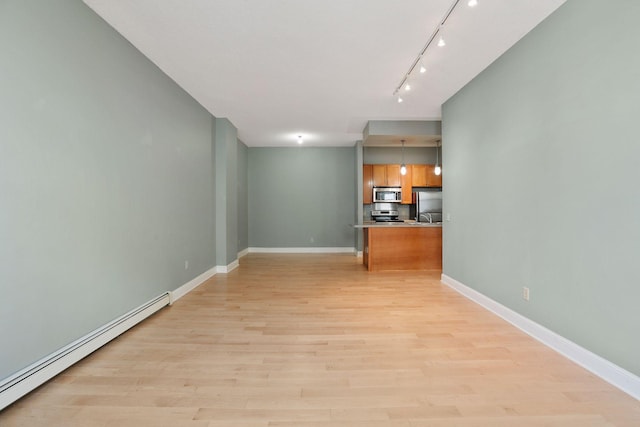 interior space with track lighting, light wood finished floors, baseboards, and baseboard heating