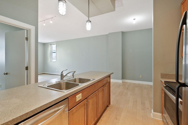 kitchen featuring brown cabinets, pendant lighting, a sink, stainless steel appliances, and light wood-style floors