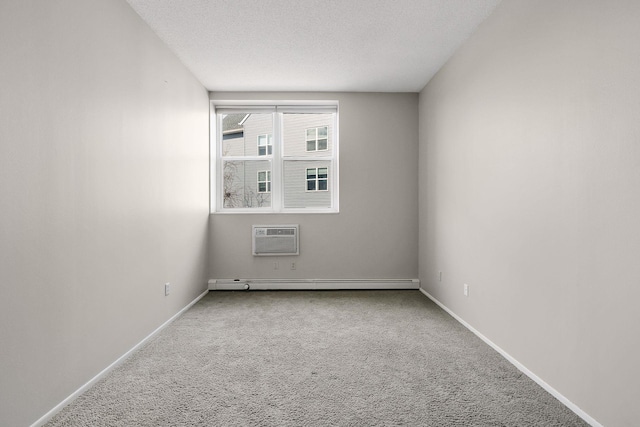 empty room with baseboards, a wall mounted AC, a baseboard radiator, a textured ceiling, and carpet flooring