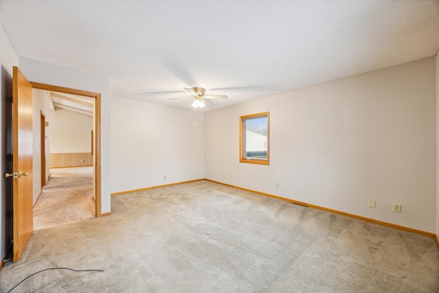 spare room featuring light carpet, baseboards, a textured ceiling, and ceiling fan