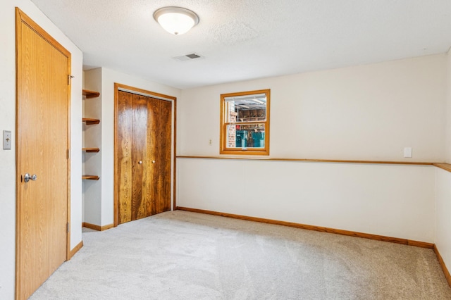 unfurnished bedroom featuring baseboards, visible vents, a closet, a textured ceiling, and carpet flooring