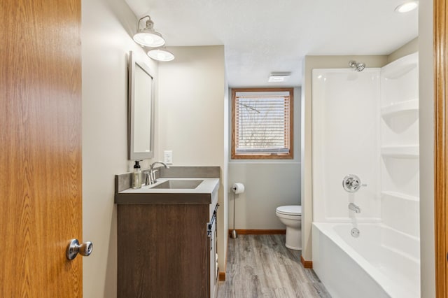 bathroom with toilet, wood finished floors, baseboards, bathing tub / shower combination, and vanity