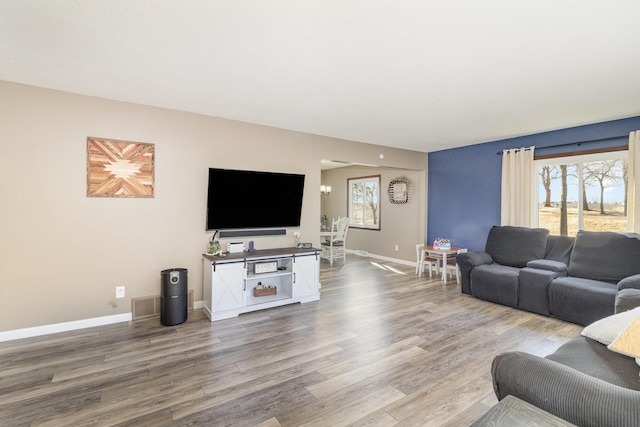 living area with visible vents, plenty of natural light, wood finished floors, and baseboards