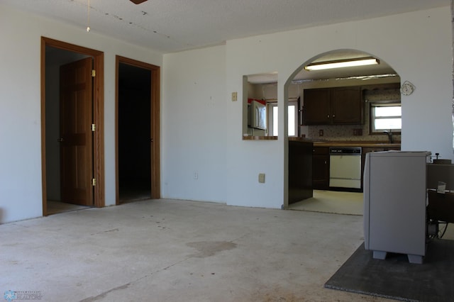 203 4th St, Argusville, ND 58005 - kitchen with white dishwasher, arched walkways, concrete flooring, a sink, and dark brown cabinets