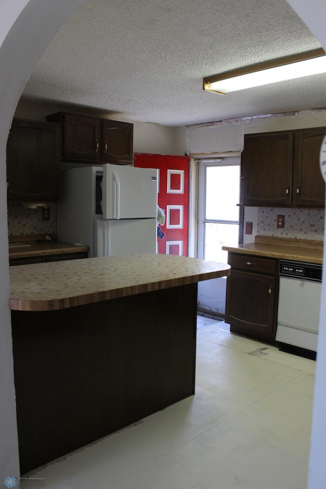 203 4th St, Argusville, ND 58005 - kitchen with white appliances, dark brown cabinets, a textured ceiling, arched walkways, and backsplash