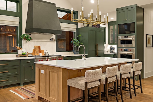 kitchen featuring light countertops, green cabinetry, light wood-type flooring, and wall chimney exhaust hood