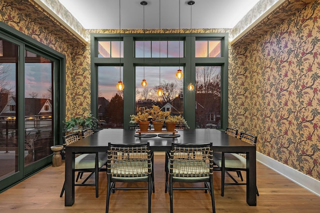 dining area with baseboards, wallpapered walls, and wood finished floors