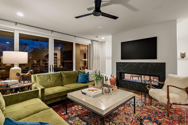 living room featuring ceiling fan, a fireplace, and wood finished floors