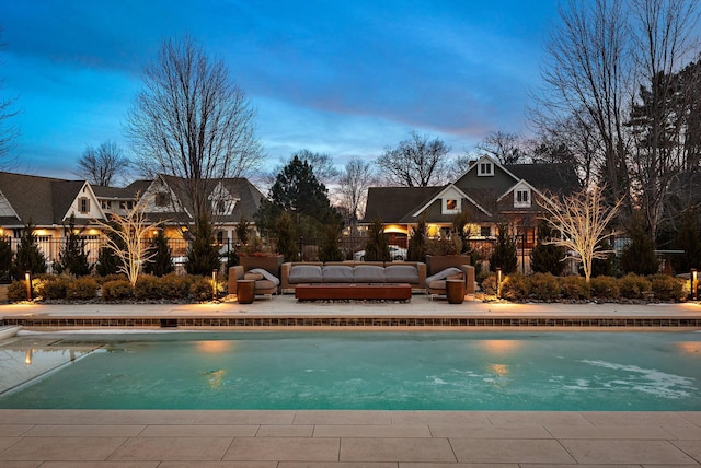 pool at dusk featuring fence, a patio, an outdoor living space, and an outdoor pool