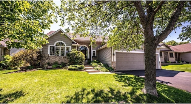 view of front of home with aphalt driveway, an attached garage, brick siding, and a front lawn