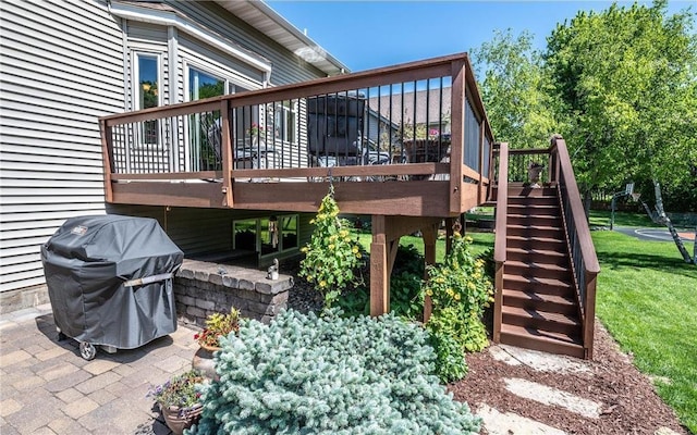 deck featuring a lawn, a grill, stairs, and a patio