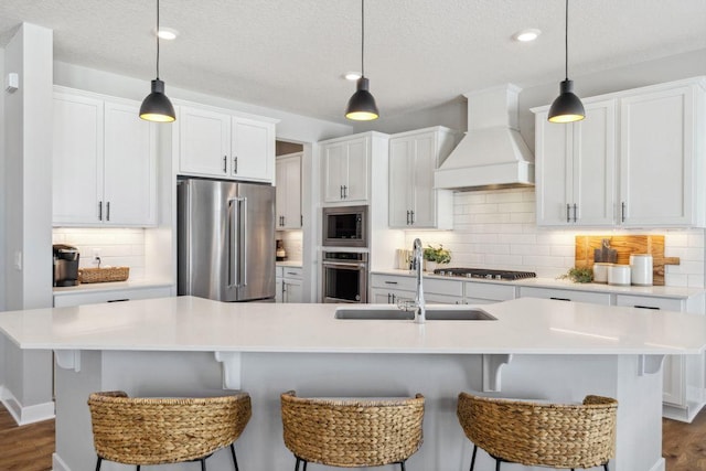 kitchen with a sink, custom exhaust hood, appliances with stainless steel finishes, and white cabinets