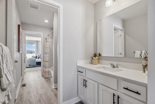 full bathroom featuring visible vents, curtained shower, baseboards, wood finished floors, and vanity