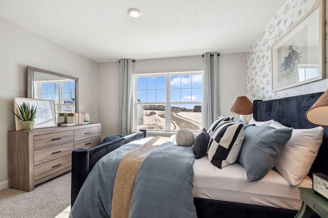 bedroom with light carpet, a textured ceiling, and wallpapered walls