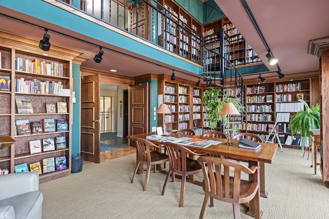 carpeted dining room with track lighting, built in features, and a towering ceiling