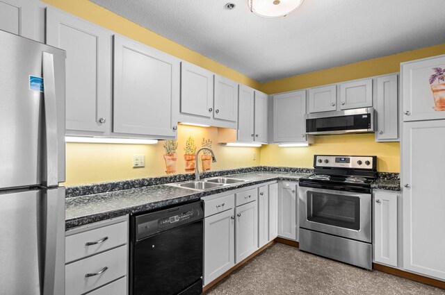 kitchen featuring dark countertops, white cabinetry, stainless steel appliances, and a sink