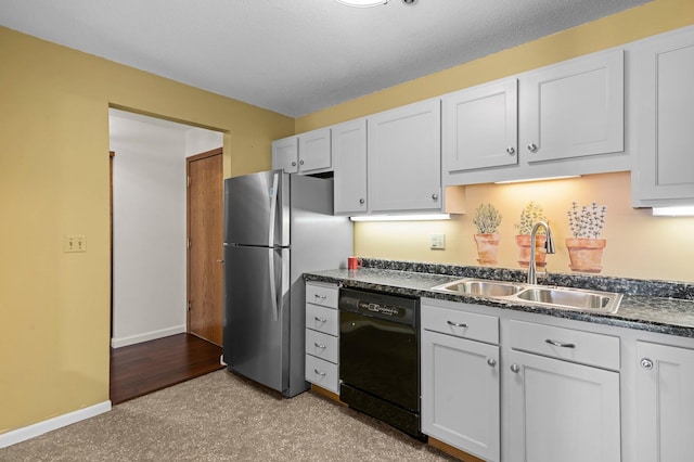 kitchen with baseboards, freestanding refrigerator, a sink, black dishwasher, and dark countertops