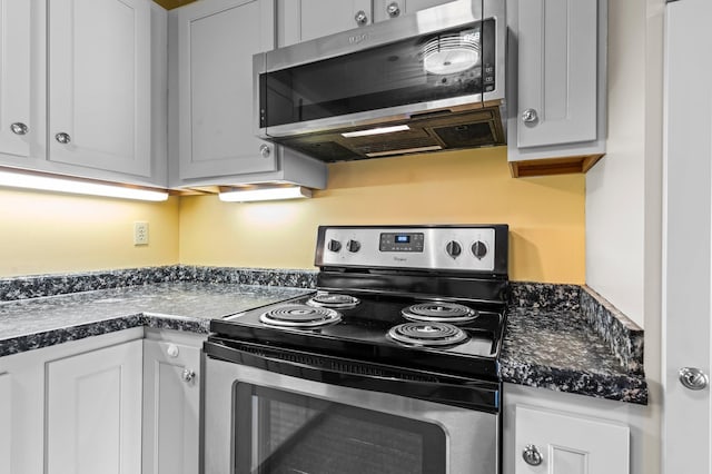 kitchen with stainless steel appliances, dark countertops, and white cabinets